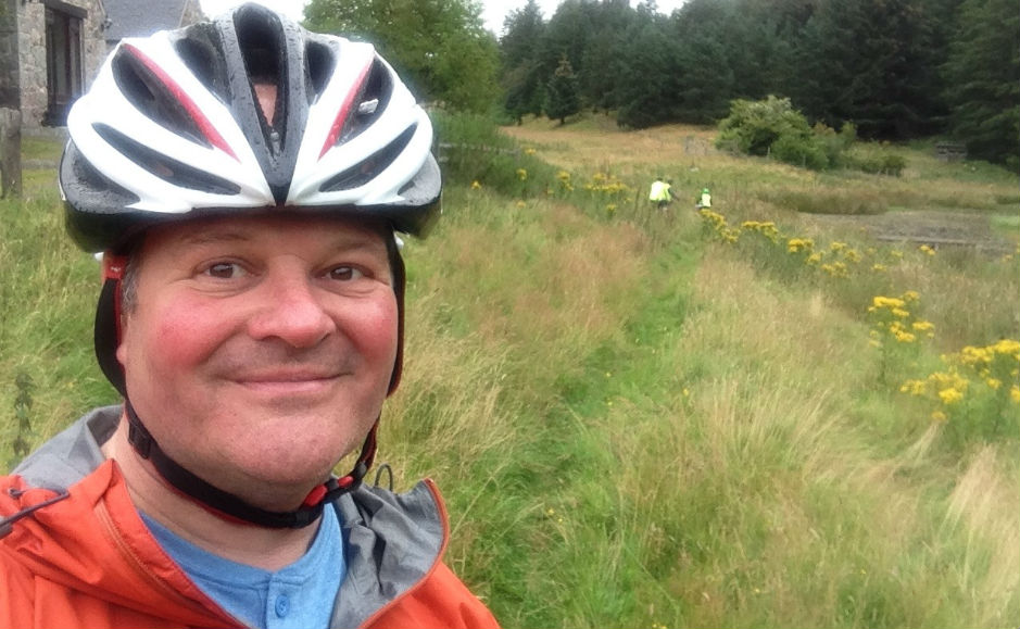 Rev Robert Brookes cycling through a field