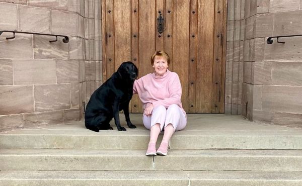 Rev Dr Karen Fenwick sitting on the church stairs with her dog
