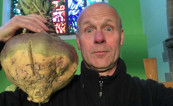 Rev Stewart Weaver holding an enormous turnip on his shoulder