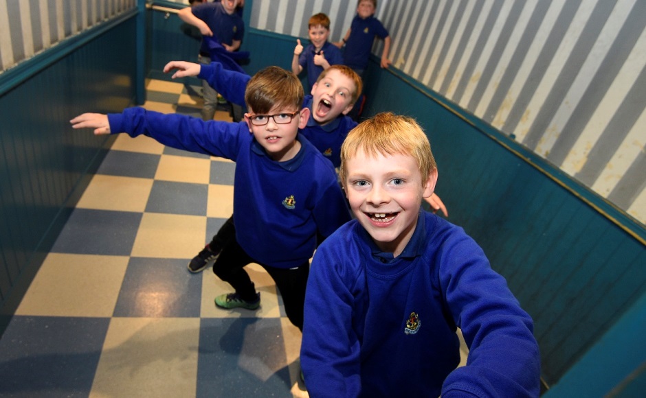 Boys enjoy visual illusions in the Ames room