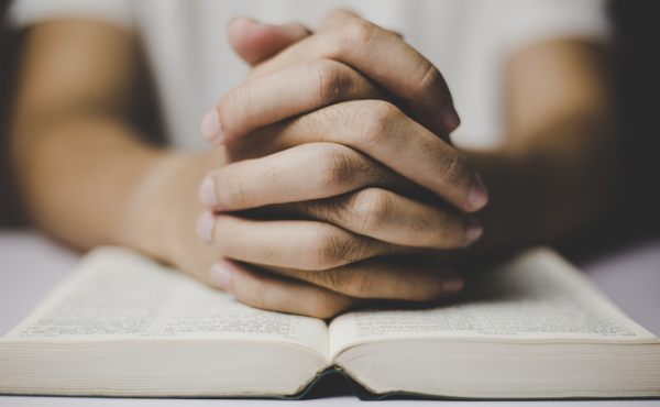 Hands in prayer over Bible
