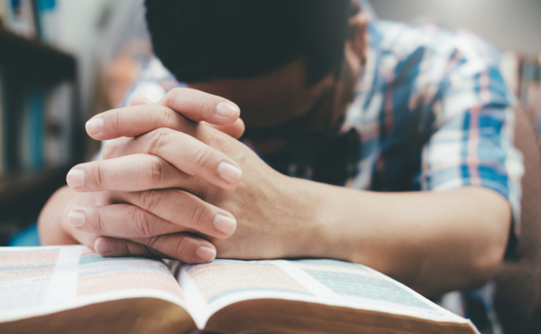 Man praying over a Bible