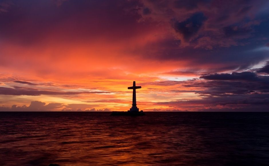 Cross on a rock in the sea at dusk