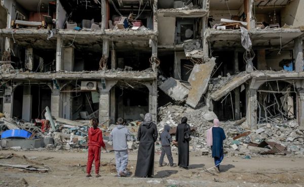 A family looks at an apartment block destroyed by a missile strike. Jalaa Street, Gaza City, 21 February 2024. Credit: Christian Aid/Omar Al-Qattaa