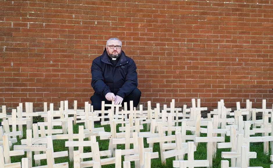 Rev Brian Casey with crosses representing the deaths of drug users