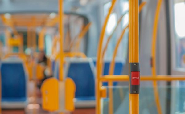 The inside of an empty bus with a stop button in the foreground of the image.